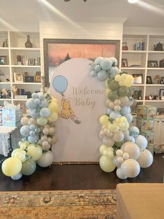 balloon arch with welcome baby sign and winnie the pooh balloons in front of bookshelves