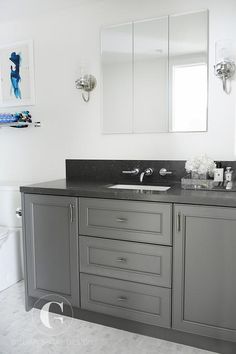 a bathroom with gray cabinets and white walls