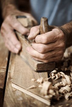 a man working with wood shavings on a wooden table