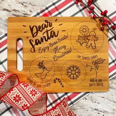 a wooden cutting board with the words dear santa and other christmas related items on it