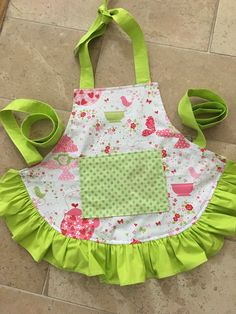 the apron is made out of fabric and has green trim around it, along with ribbon ties