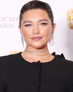 an image of a woman with earrings on her head and wearing a black dress, posing for the camera