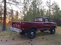 a red pick up truck parked in the woods