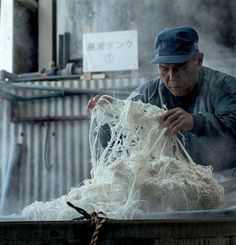 an old man is making something out of yarn