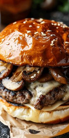 a cheeseburger with mushrooms and onions is on a piece of brown wax paper