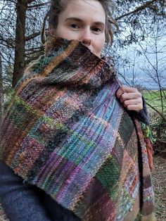 a woman wearing a multicolored shawl in the woods with her mouth open