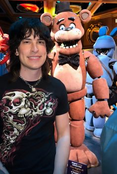 a man standing next to three stuffed animals in front of him and smiling at the camera