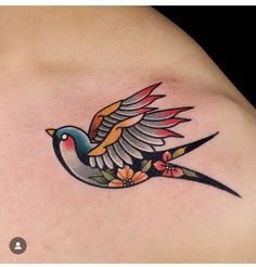 a bird tattoo on the back of a woman's shoulder, with flowers around it