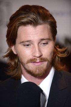 a close up of a person wearing a suit and tie with a microphone in front of him