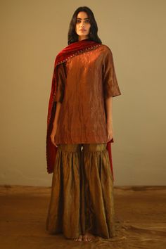 Rust red kurta with sequin embroidery and round-neck. Paired with gold sharara.
Components:2
Neckline:Round
Sleeve Length:Three quarter
Fabric:Handloom Tissue 
Color:Red,Gold
Note: Dupatta worn by the model is not for sale - Aza Fashions Tissue Sharara, Kurta And Sharara Set, Red Suits, Kurta And Sharara, Outfit Reference, Sharara Pants, Red Kurta, Outfit Collection, Traditional Attires