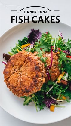 a white plate topped with fish cakes next to a pile of salad greens and radishes