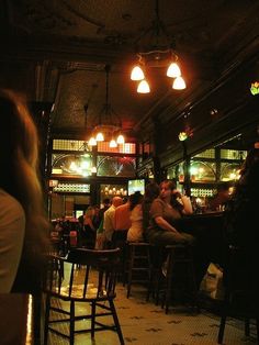 a group of people sitting at tables in a room with lights on the ceiling and floor