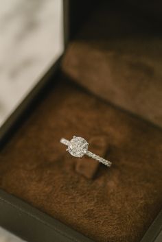 an engagement ring in a box on top of a table