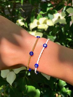 a woman's arm with two evil eye bracelets on top of her wrist