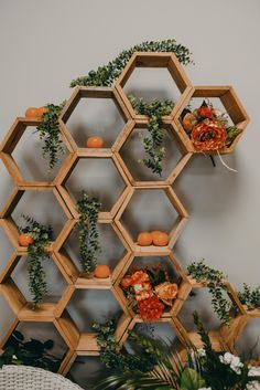 an arrangement of flowers and greenery is arranged on the wall next to a shelf with hexagonal shelves