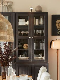 a dining room table with plates and glasses on it, next to a china cabinet