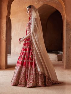 Editor's Note Embrace allure in our scarlet red raw silk lehenga choli set. The scalloped net dupatta is a masterpiece, adorned with delicate 3D flowers intricately embroidered in gold zari, dabka, sequins, beadwork, and crystals. This ensemble harmonizes traditional craftsmanship and contemporary elegance, capturing attention with its exquisite details and luxurious flair. Note: Gold veil dupatta is for styling purposes only. Fabric: Raw silk and net Color: Red Components: Lehenga, blouse and d Bridal Clothes, Gold Veil, Bridal Lehenga Online, Silk Lehenga Choli, Raw Silk Lehenga, Bridal Lehenga Collection, Designer Bridal Lehenga, Bridal Lehenga Red, Lehenga Online