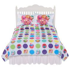 a bed with colorful polka dot bedspread and pillow cases on top of it