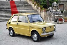 an old yellow car parked in front of some steps