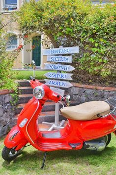 a red scooter is parked in front of a sign that points to different destinations