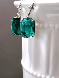 I love the clean simple lines and the sheer emerald green color of these Art Deco style estate earrings. They feature emerald green octagon rhinestone beads and silver plated leverback ear wires. These elegant earrings measure 1 1/4 inches long. Perfect for everyday or evening. ABOUT THIS COLLECTION What are the three style essentials Jazz Age flappers like Clara Bow, Louise Brooks, and Zelda Fitzgerald have in common? Red lipstick, bobbed haircuts, and fabulous dangle earrings. My Flapper Colle Formal Rectangular Earrings With May Birthstone, Formal Green Drop Earrings, Formal Green Dangle Earrings, Classic Green Drop Earrings, Green Drop Earrings For Formal Occasions, Green Dangle Earrings For Formal Occasions, Formal May Birthstone Crystal Drop Earrings, Classic Green Earrings For May Birthstone, Elegant Rectangular May Birthstone Earrings