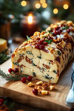 a loaf of cheese with cranberries and nuts on a cutting board