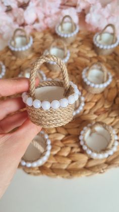 someone is holding up some rings and bracelets on a woven basket with flowers in the background