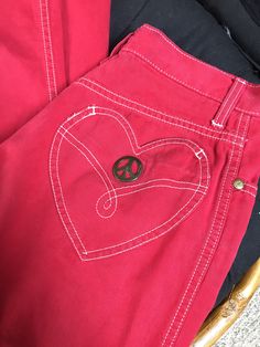 "90's Moschino red cotton peace & love jeans. The jeans have a high waist with a loose, slightly tapered leg. Condition is pre-worn, good. There are light signs of wear (some small, scattered black spots) slight fade, but nothing that stands out. Overall the look is still very good. Made in Italy Labeled size 29 Shown pinned on an XS, 5'10\" tall mannequin Measurements Waist 27 Hips 36 Length 40.5 Inseam 30 Rise 11" Vintage Pink Cotton Jeans, Red 90s Bottoms With Pockets, Retro Red Jeans For Spring, Retro Red Spring Jeans, 90s Style Pink Cotton Jeans, Vintage Pink Straight Leg Jeans, 90s Style Red Cotton Jeans, Retro Red Cotton Pants, Retro Red Cotton Bottoms