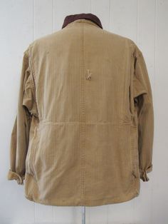 "Vintage 1930s or 40s hunting jacket. Made of khaki color herringbone twill cotton. Has a salt and pepper brown corduroy collar, tan corduroy cuffs, button front, five pockets, two shotgun shell pockets and a large back game pouch. Label reads: BLUE BILL BY THE MAKERS OF \"RED HEAD\". Size large. Actual measurements are: 46\" at the chest 48\" at the waist 21\" shoulder seam to shoulder seam 23\" shoulder seam to end of cuff 29.5\" overall length In very good condition with a 1\" hole at back an Vintage Brown Utility Jacket With Corduroy Collar, Vintage Long Sleeve Utility Jacket For Hunting, Vintage Brown Cotton Utility Jacket, Vintage Brown Cotton Sport Coat, Vintage Cotton Sport Coat For Fall, Vintage Beige Utility Jacket With Pockets, Vintage Utility Jacket For Hunting In Fall, Vintage Beige Cotton Utility Jacket, Vintage Cotton Hunting Outerwear