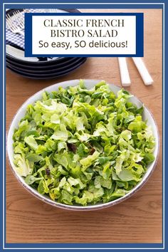 a bowl filled with lettuce sitting on top of a table next to plates