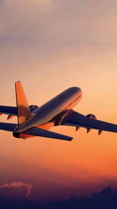 an airplane is flying in the sky at sunset