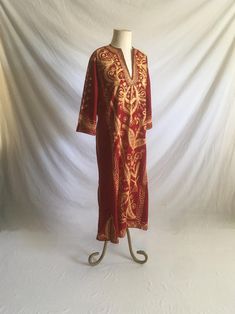 1970s handmade kaftan shirt dress red velvet gold color brocade w/silver accenting thread deep v pullover 3/4 sleeve ankle length, depending on wearer's height 7" side slits good vintage condition, light wear light irregularities normal to handmade item no size tag, see below measures, lying flat, shoulder-17" sleeve-17" chest-21 1/2" waist-19" hip-22" length-51"     We do not offer returns or refunds unless something is grossly misrepresented. Please contact us within 2 business days of receivi Fitted Long Sleeve Kaftan With Gold Embroidery, Festive Gold Thobe For Festivals, Bohemian Kaftan With Gold Embroidery For Festivals, Bohemian Thobe With Gold Embroidery For Festive Occasions, Bohemian Festive Thobe With Gold Embroidery, Festive Bohemian Thobe With Gold Embroidery, Bohemian Long Sleeve Gold Kaftan, Bohemian Kaftan With Gold Embroidery, Festive Red Kaftan With Gold Embroidery