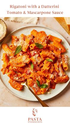 a white plate topped with pasta covered in tomato sauce and parmesan cheese next to bread