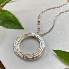 This elegant necklace offers up a unique combination of playfulness & timeless style. Nine organically shaped & uniquely textured sterling silver circles layer gracefully on a lovely sterling silver double cable chain. Each ring is handcrafted individually to represent your journey through the decades. Circles are hammered flat & strong, and given a rustic sparkly texture. The circles shimmer & move gracefully with you, capturing the light & landing in various arrays. This piece is a beautiful w Adjustable Sterling Silver Jewelry For Celebrations, Silver Fusion Necklace For Anniversary, Silver Fusion Style Necklace For Anniversary, Sterling Silver Necklace For Celebration, Sterling Silver Fusion Necklace For Anniversary, Sterling Silver Round Necklace For Celebration, Silver Spiral Necklace For Anniversary, Sterling Silver Full Circle Necklace For Anniversary, Silver Birthstone Necklace For Celebration