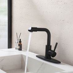 a black faucet running water from it's spout in a bathroom