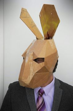 a man in a suit and tie wearing a paper mask with an animal's head on it