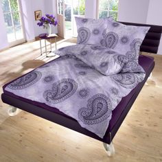 a bed with purple sheets and pillows in a room