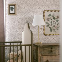 two stuffed animals sitting in a crib next to a wallpapered wall with flowers