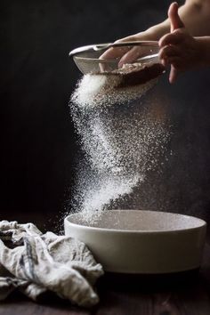 someone is sprinkling flour into a bowl