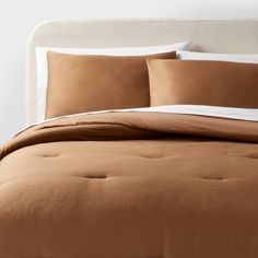 a bed with brown sheets and pillows on it