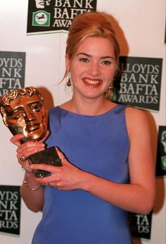 a woman in a blue dress holding an award