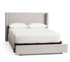 the bed is made up and has two pillows on top of it, with an ottoman underneath