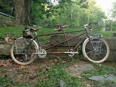 a bicycle parked next to a rock in the woods