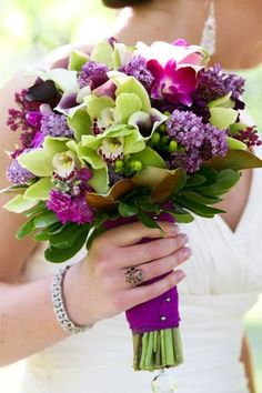 a bride holding a purple and green bouquet