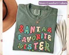 This Comfort Colors® t-shirt features the fun and festive phrase "Santa's Favorite Sister" in cute retro Christmas colors, accented with a string of twinkling Christmas lights. Made from soft, high-quality cotton, this shirt offers a relaxed fit and a cozy, vintage-inspired feel that's perfect for the holiday season. Whether you're baking cookies, playing card games, or simply enjoying the festive spirit, this crewneck shirt is a fun way to celebrate being a sister. It also makes a thoughtful gi Twinkling Christmas Lights, Mother Shirts, The Dancer, Christmas Favorites, Crew Neck Shirt, Retro Christmas, Christmas Colors, Tshirt Colors, Types Of Shirts