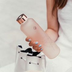 a woman holding an apple water bottle in her right hand and a white purse on the other