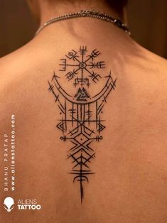 the back of a woman's neck with an arrow and compass tattoo on it