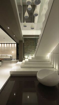 the interior of a modern house with white furniture and lights on the ceiling is lit by recessed lighting