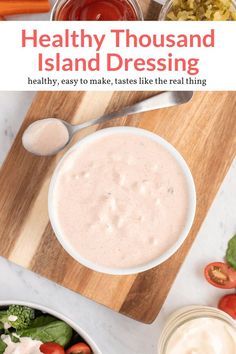 healthy thousand island dressing in a white bowl on a cutting board with tomatoes, lettuce and carrots