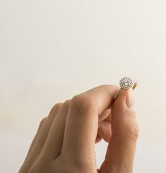 a woman's hand holding an engagement ring with a diamond center in the middle